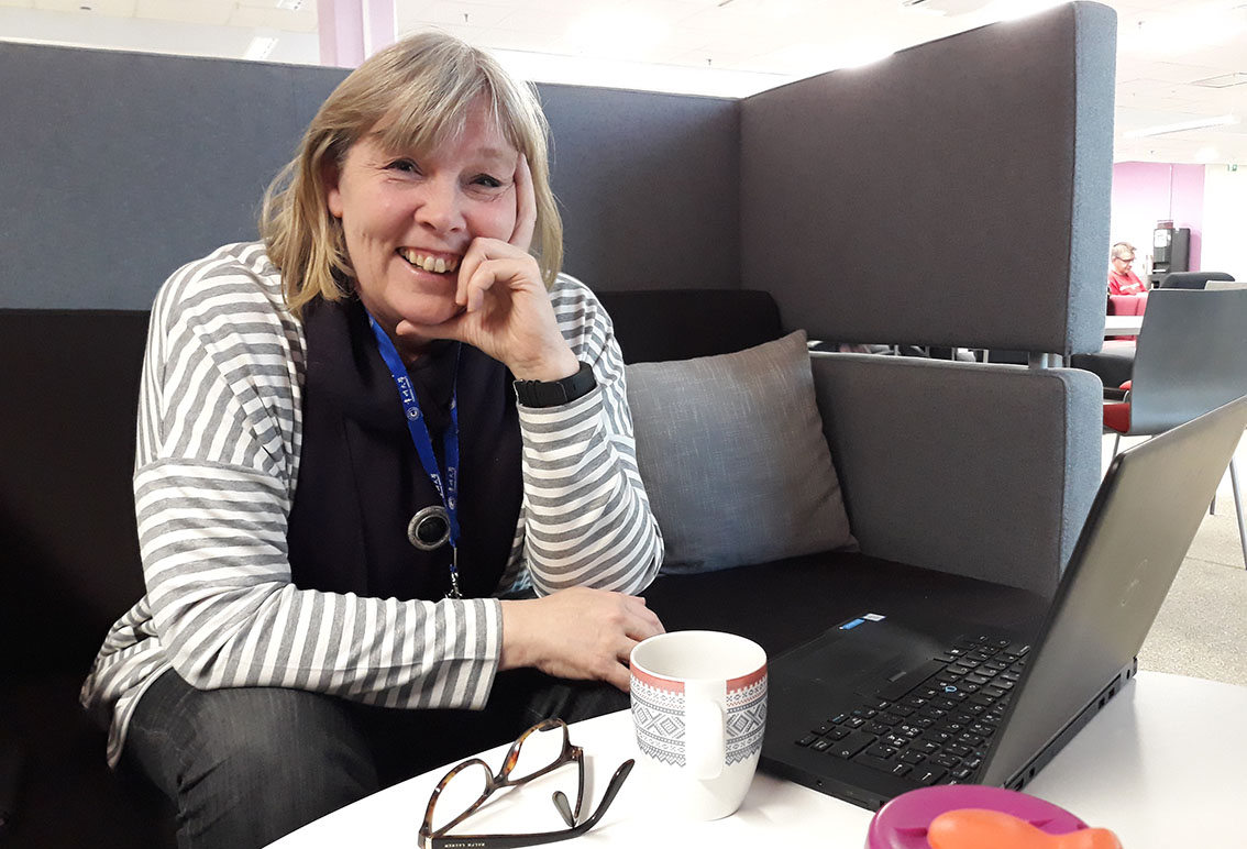 Merja Sallinen sitting and smiling at the computer