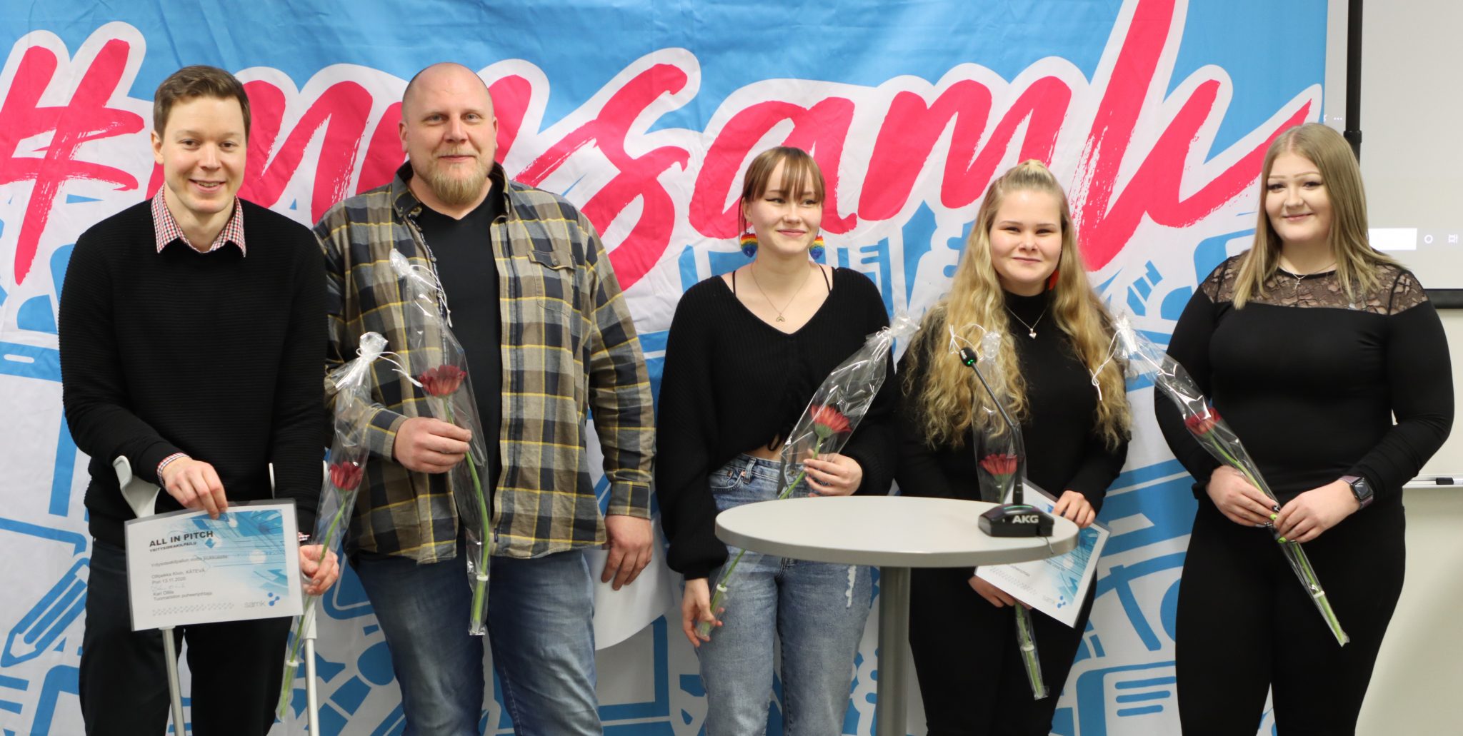 Voittajat poseeraavat yhdessä ruusujen kanssa.