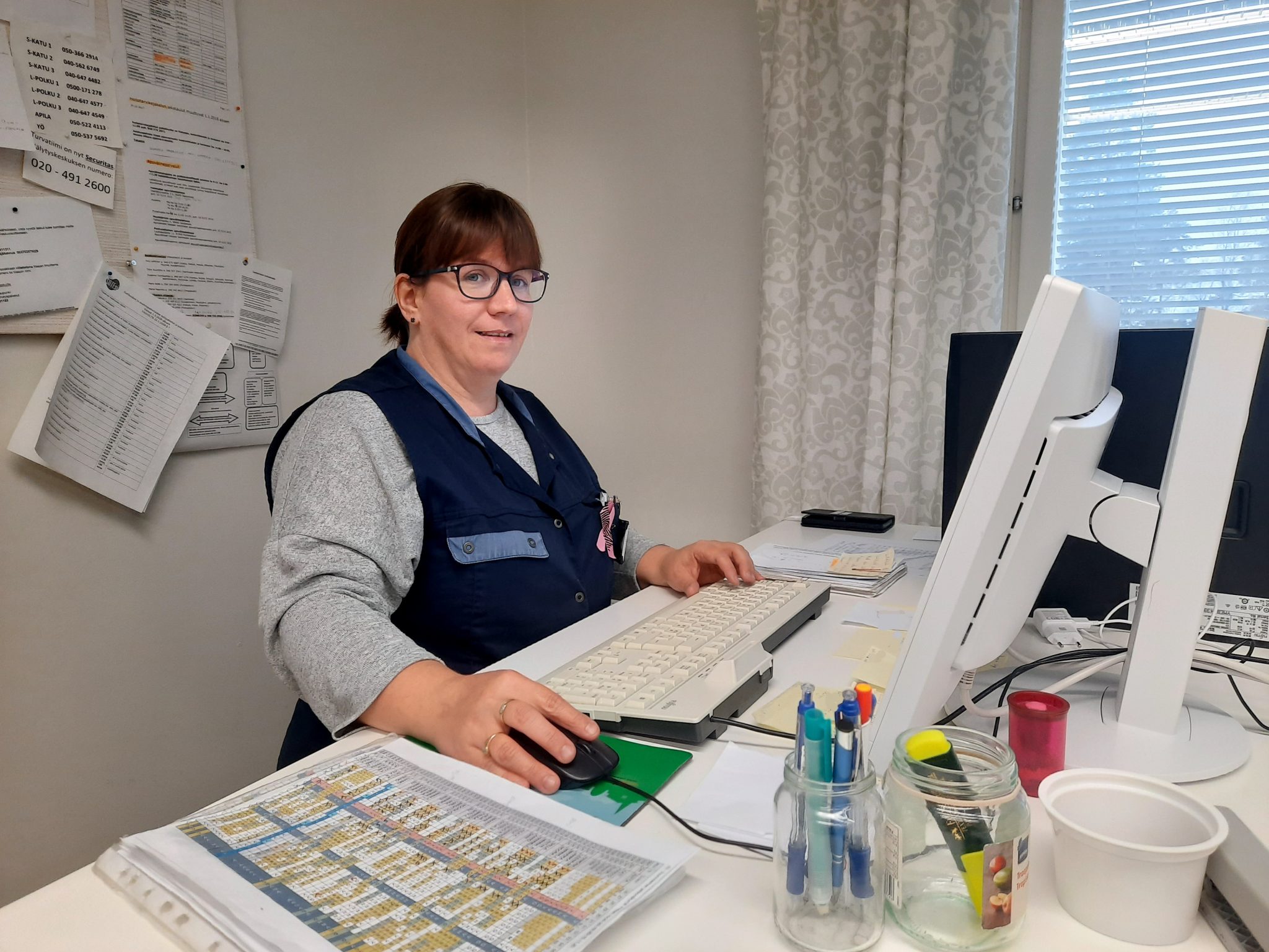 Aila Rantanen istuu työvaatteissa toimistopöytänsä äärellä.