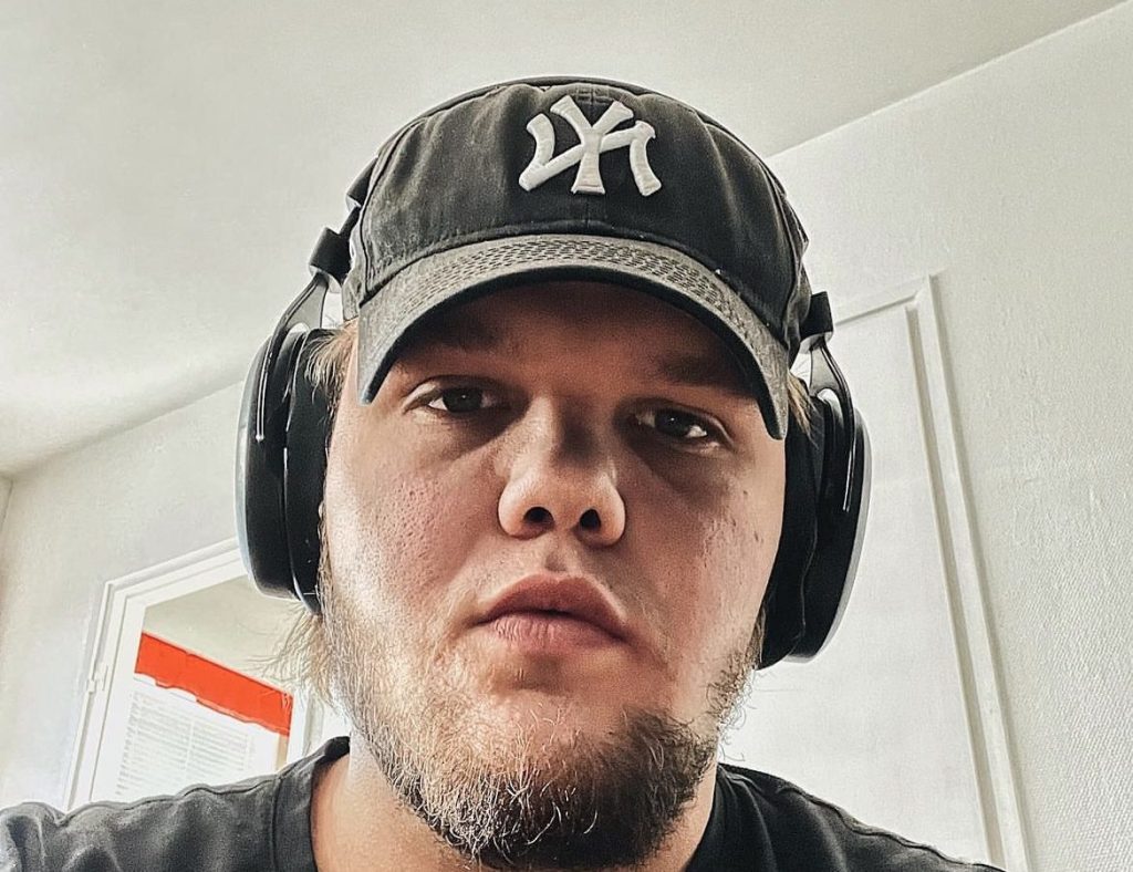 Mies kuulokkeet ja lippis päässä.