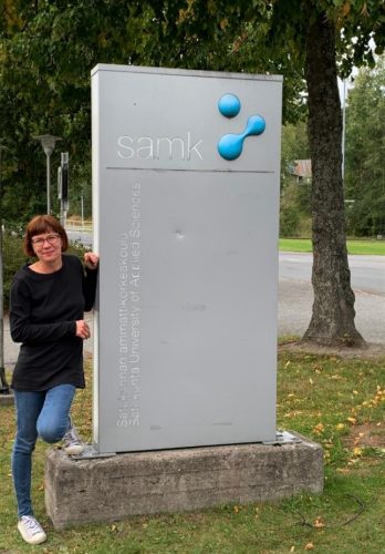 Hanna poseeraa SAMKin kyltin vieressä.