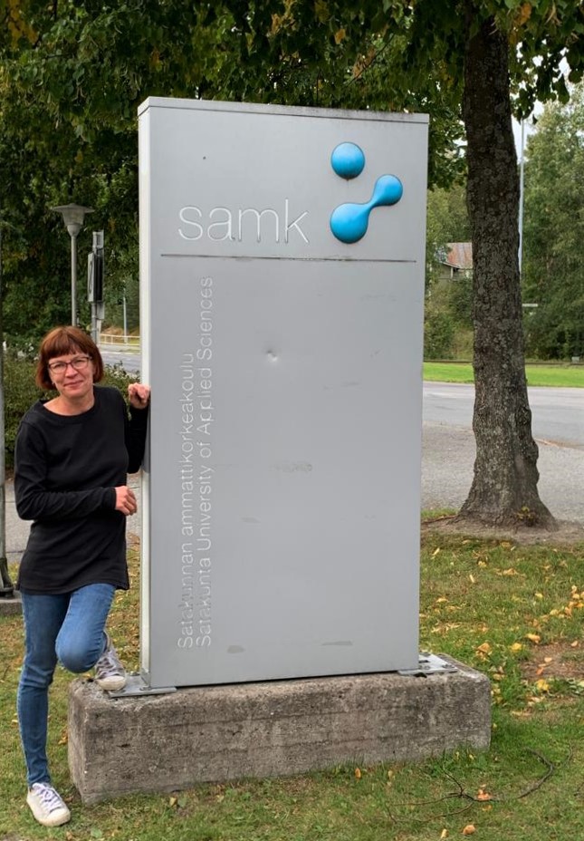 Hanna poseeraa SAMKin kyltin vieressä.
