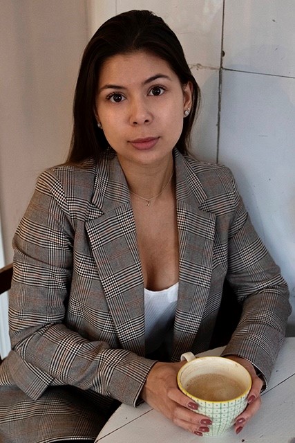 Jasmine Hannula pöydän ääressä kahvikuppi kädessä.