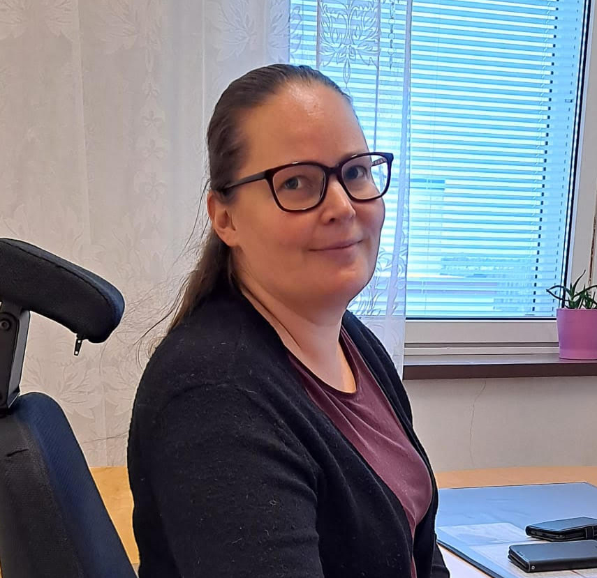 Jonna Elovaara istuu hymyillen työpöytänsä ääressä