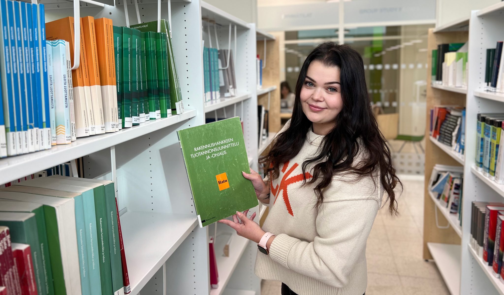 Tumma hiuksinen Julia vihreäkantinen kirja kädessään.