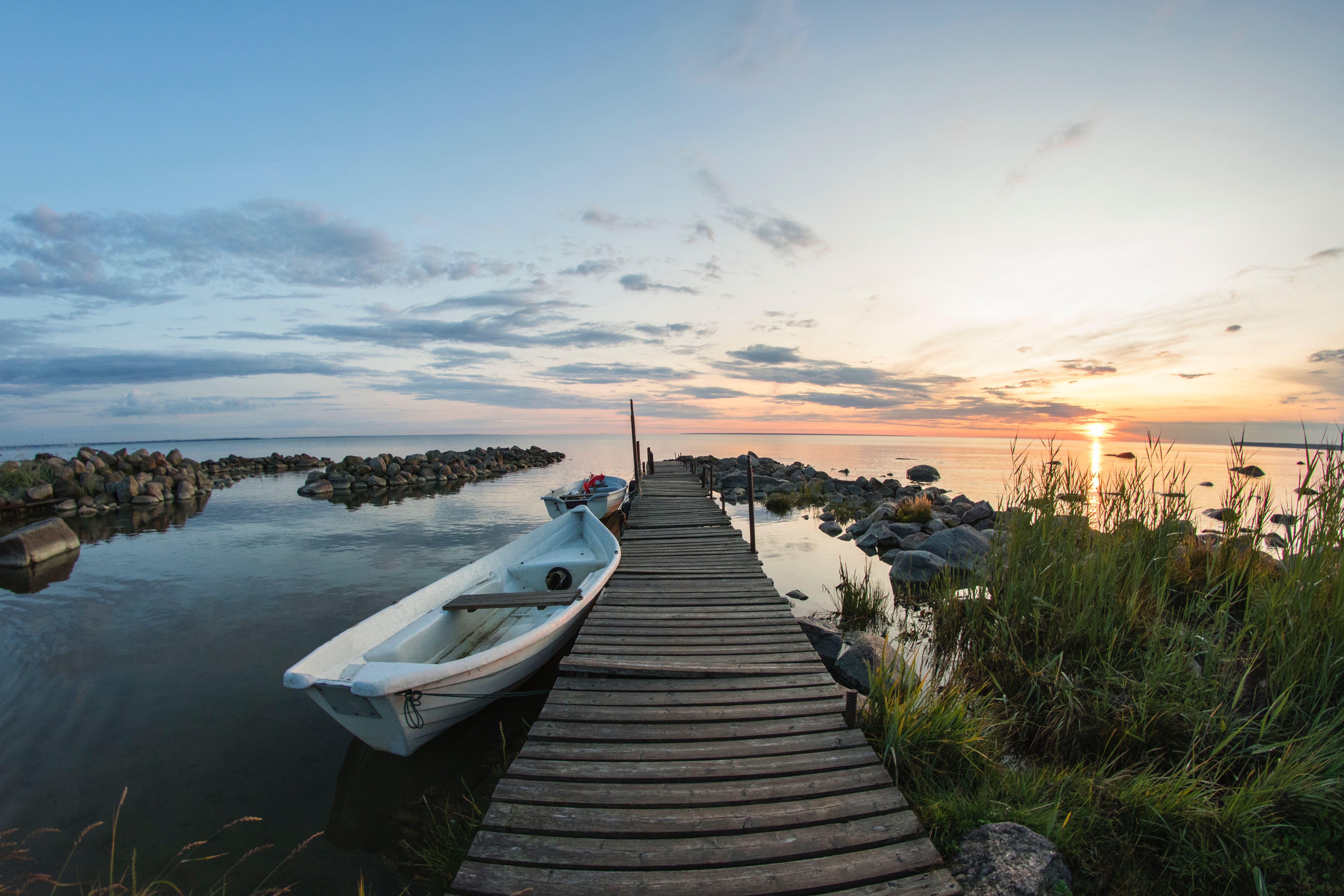 Boat beside pier at sunset.