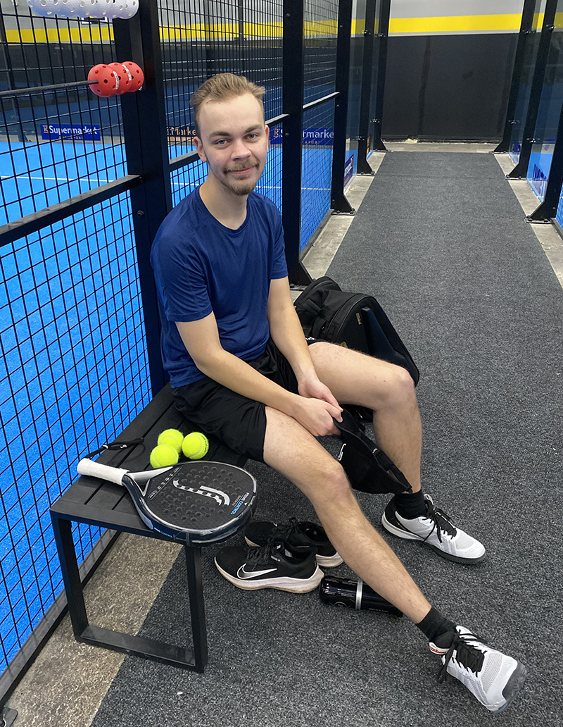 Julius Nieminen istuu penkillä padel-kentän laidalla.