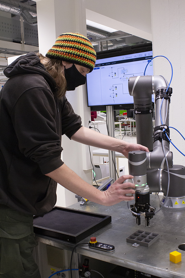 Mies käyttää yhteistyörobottia.