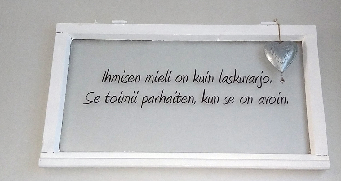 Valkopuitteinen ikkuna, jossa on aforismi.