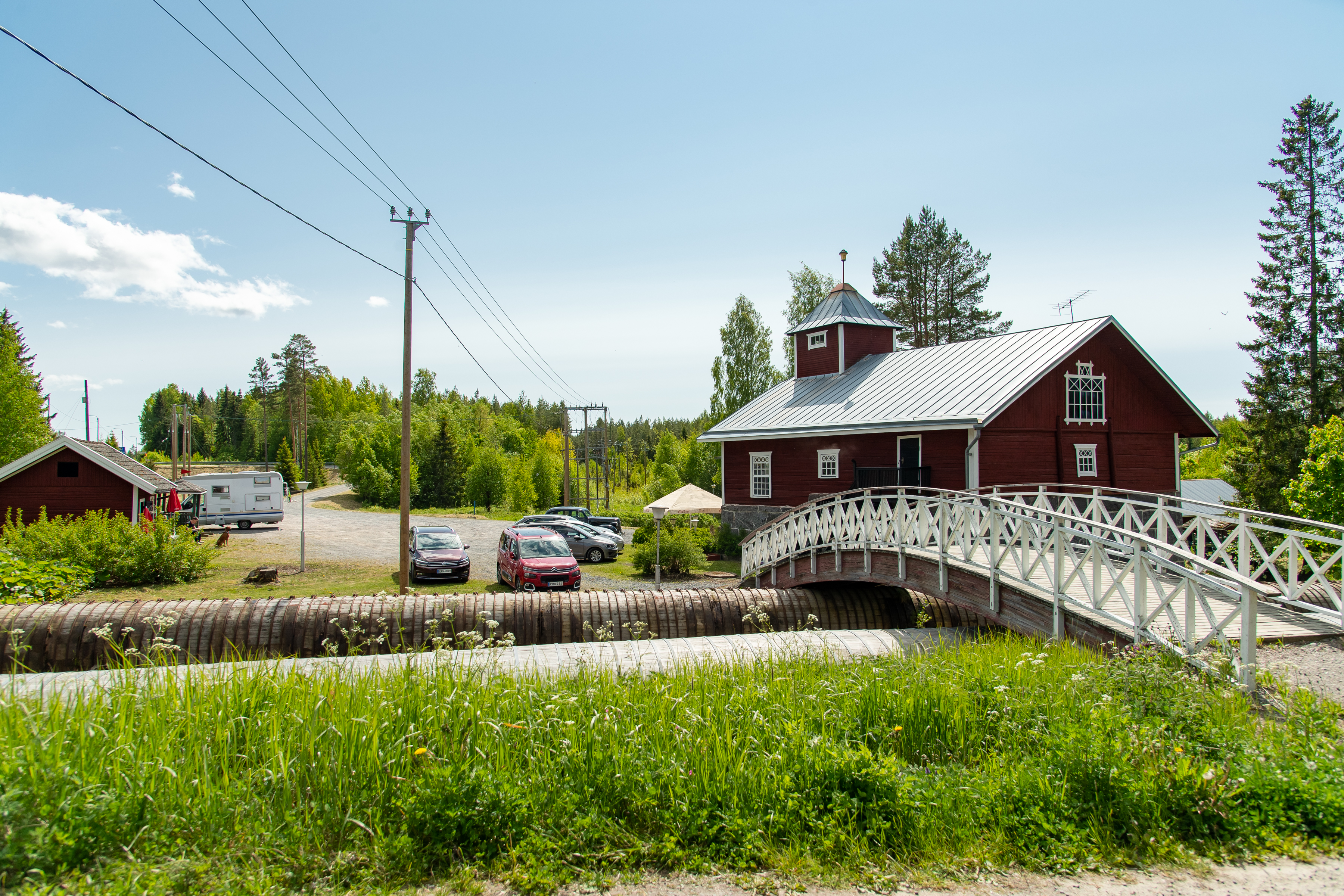 Red cottage next to wooden bridge.