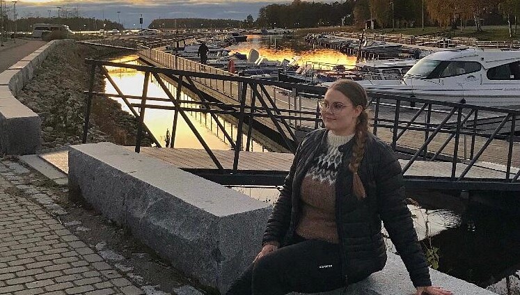 Roosa istuu venelaiturin vieressä.