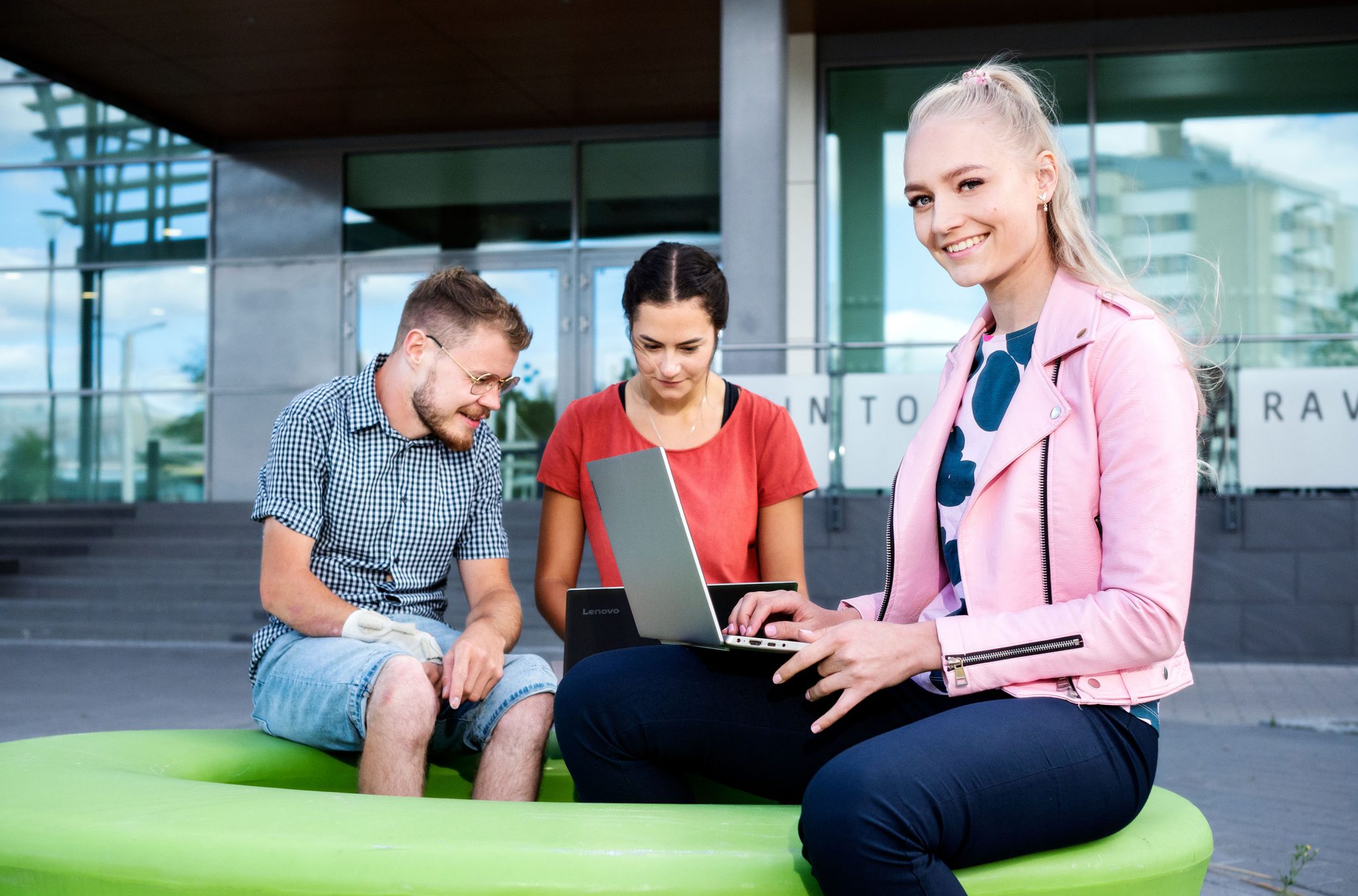 SAMK students smiling and working with laptops front of SAMK Campus Pori.