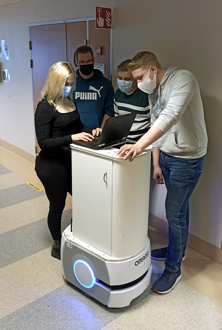 Kuvassa neljä opiskelijaa on mobiilirobotin ympärillä.