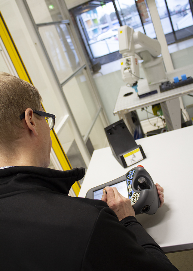 Mies käyttää ABB-robotin ohjainta.