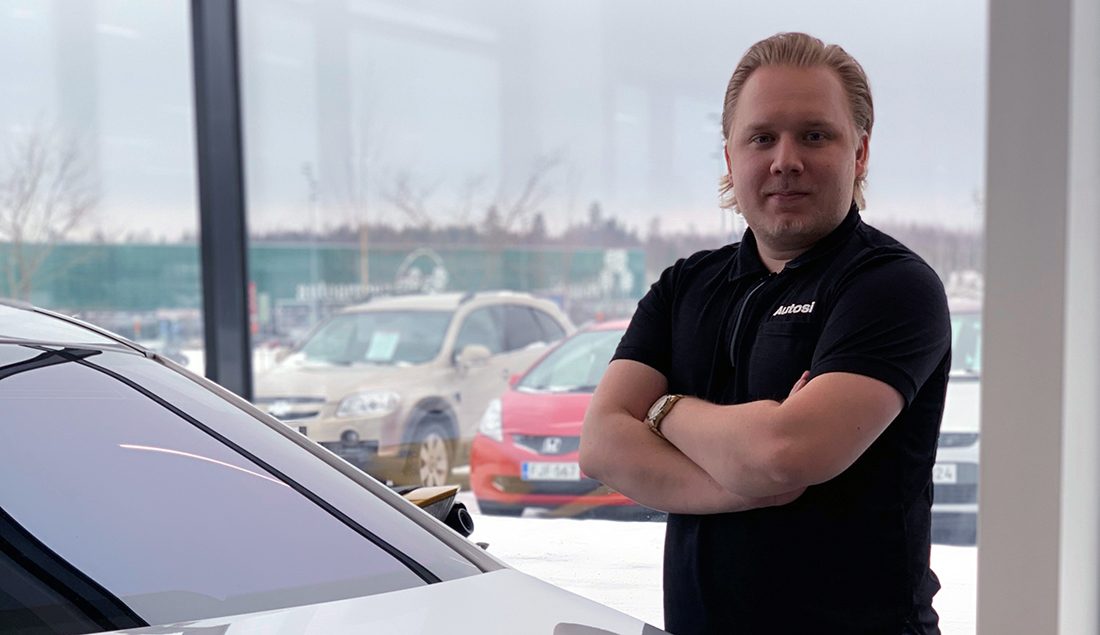 Leevi Juutilainen seisoo autoliikkeessä auton vieressä.