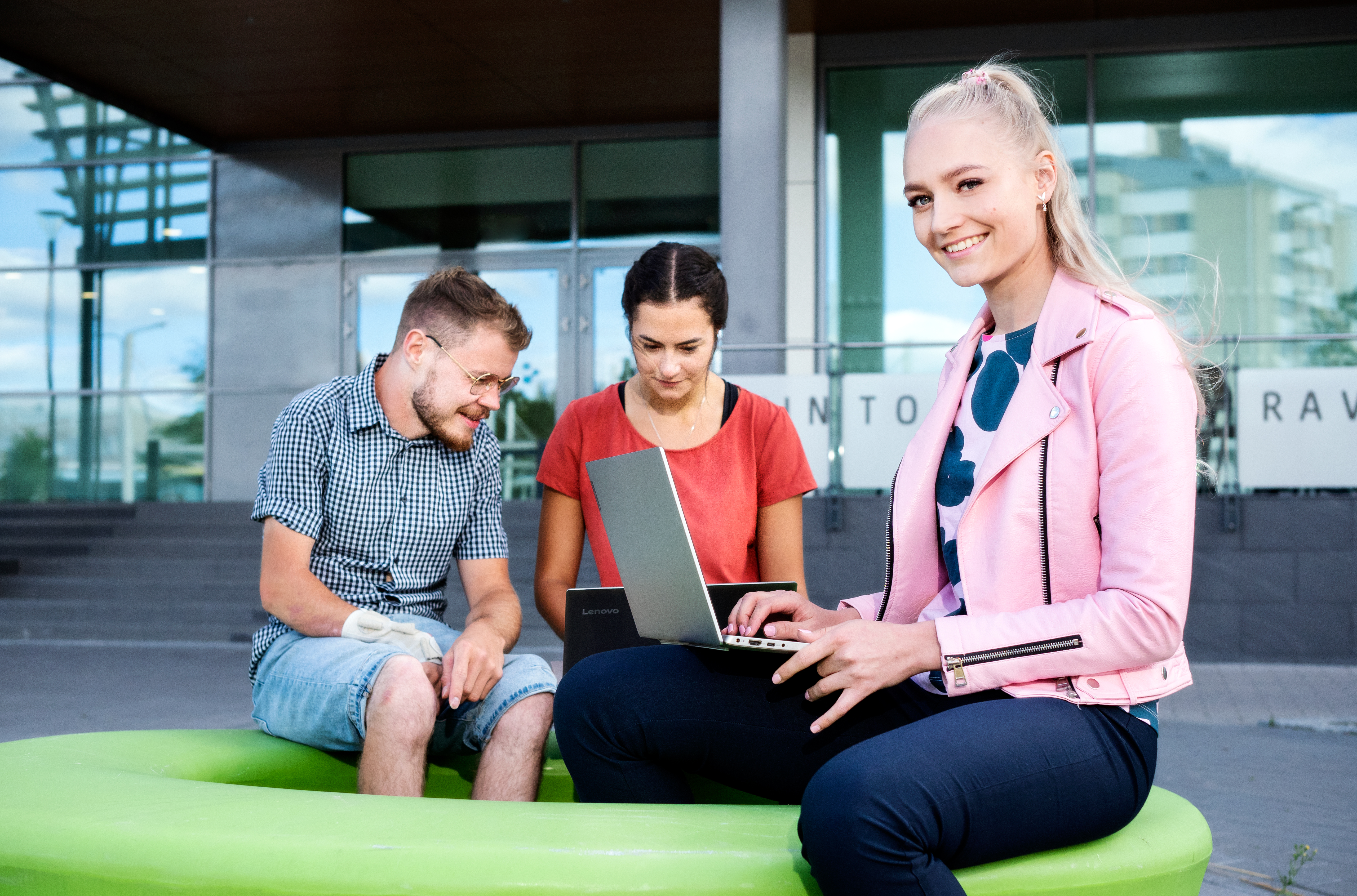 SAMK students working with laptop outside campus in summer.
