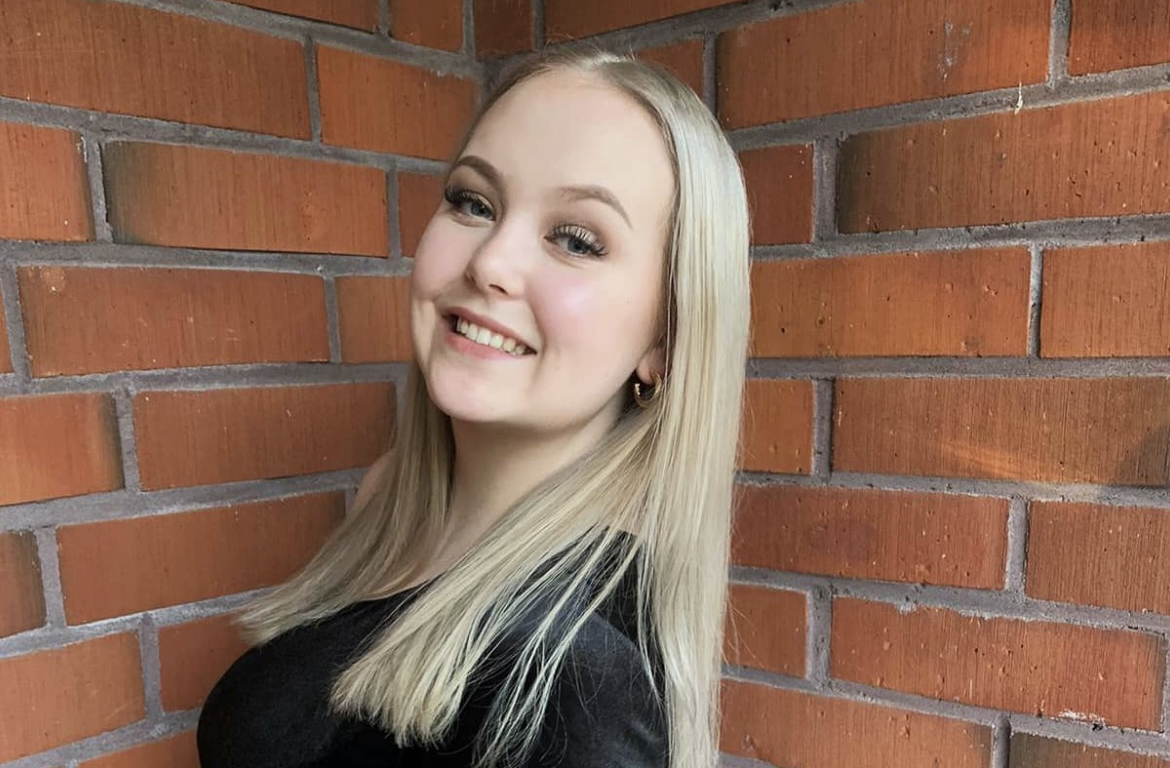 Elina Jalonen seisoo tiiliseinän vieressä