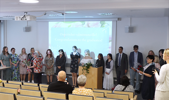 Graduating students stand in front of the audience.