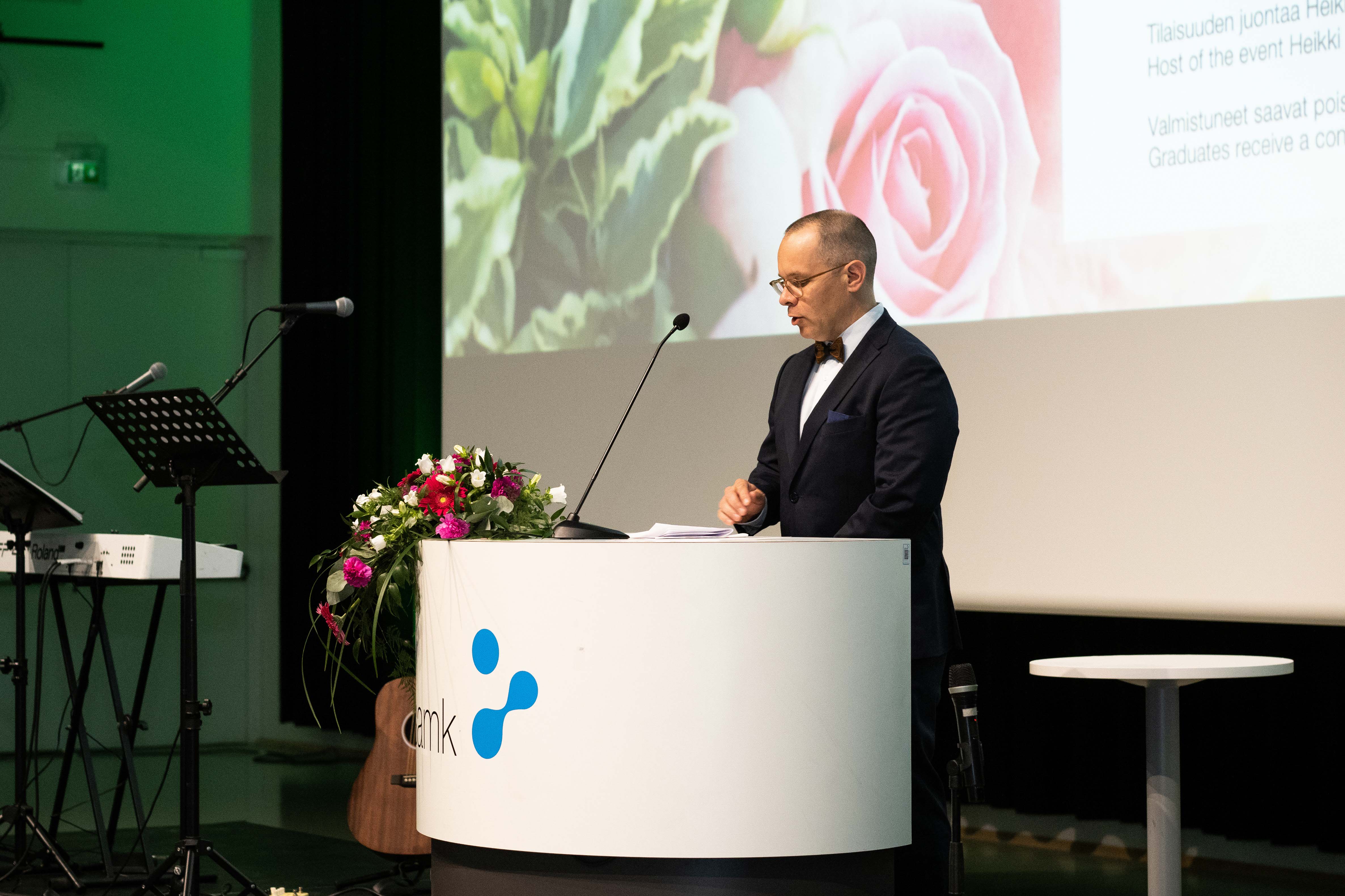 A male person speaks to the audience from a lectern.