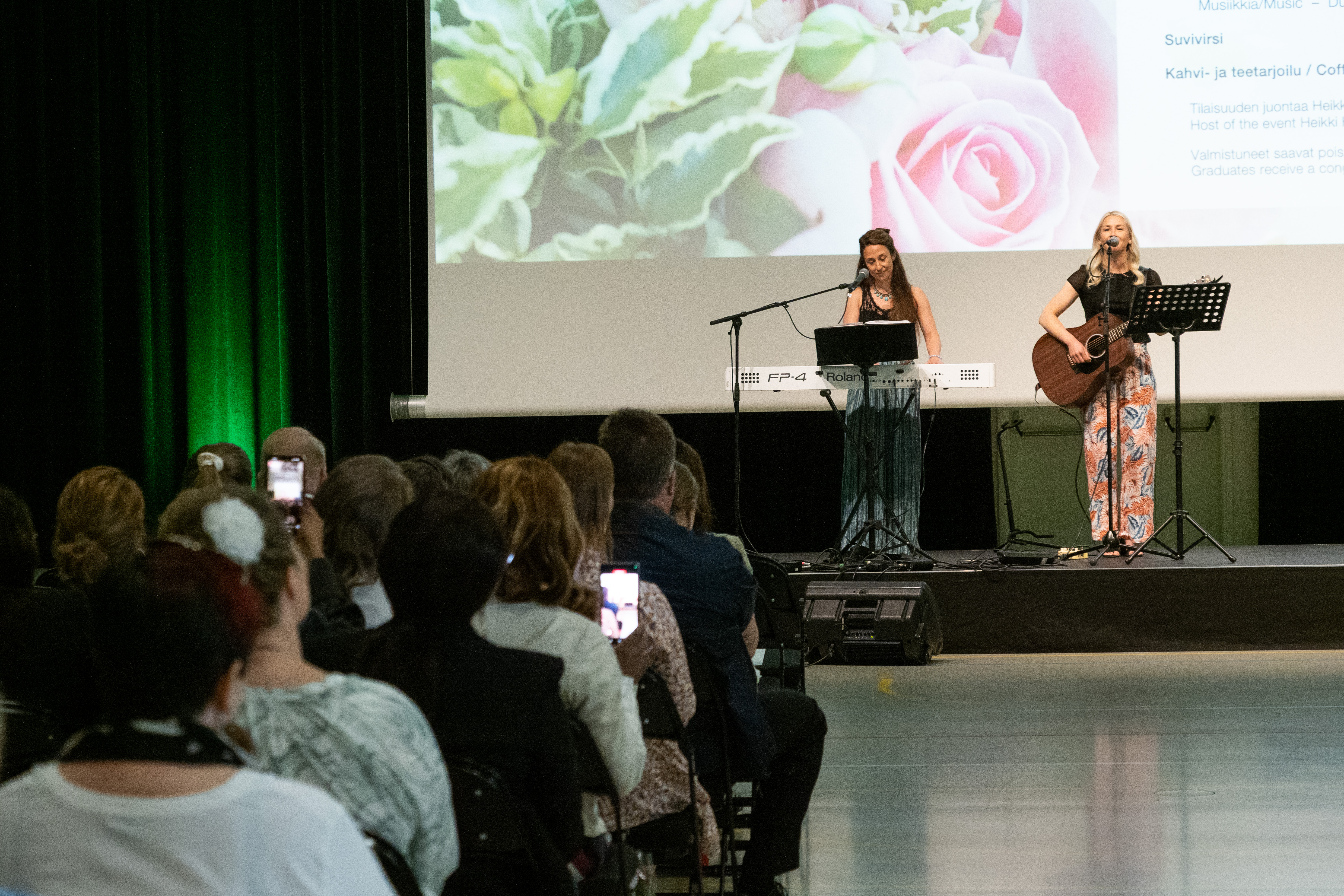 Two women perform on stage with guitar and keyboards.
