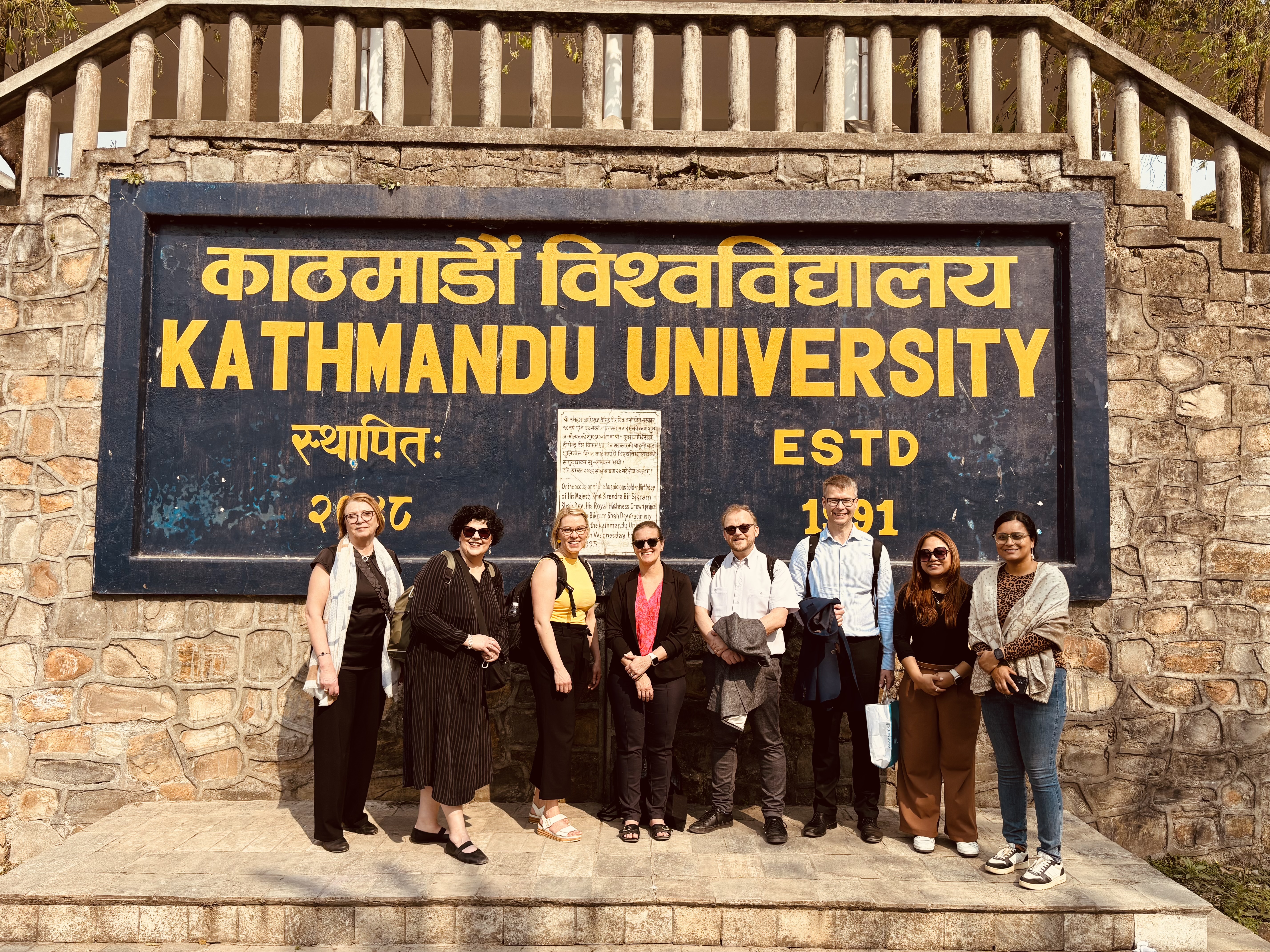 People posing outside in front of the university.