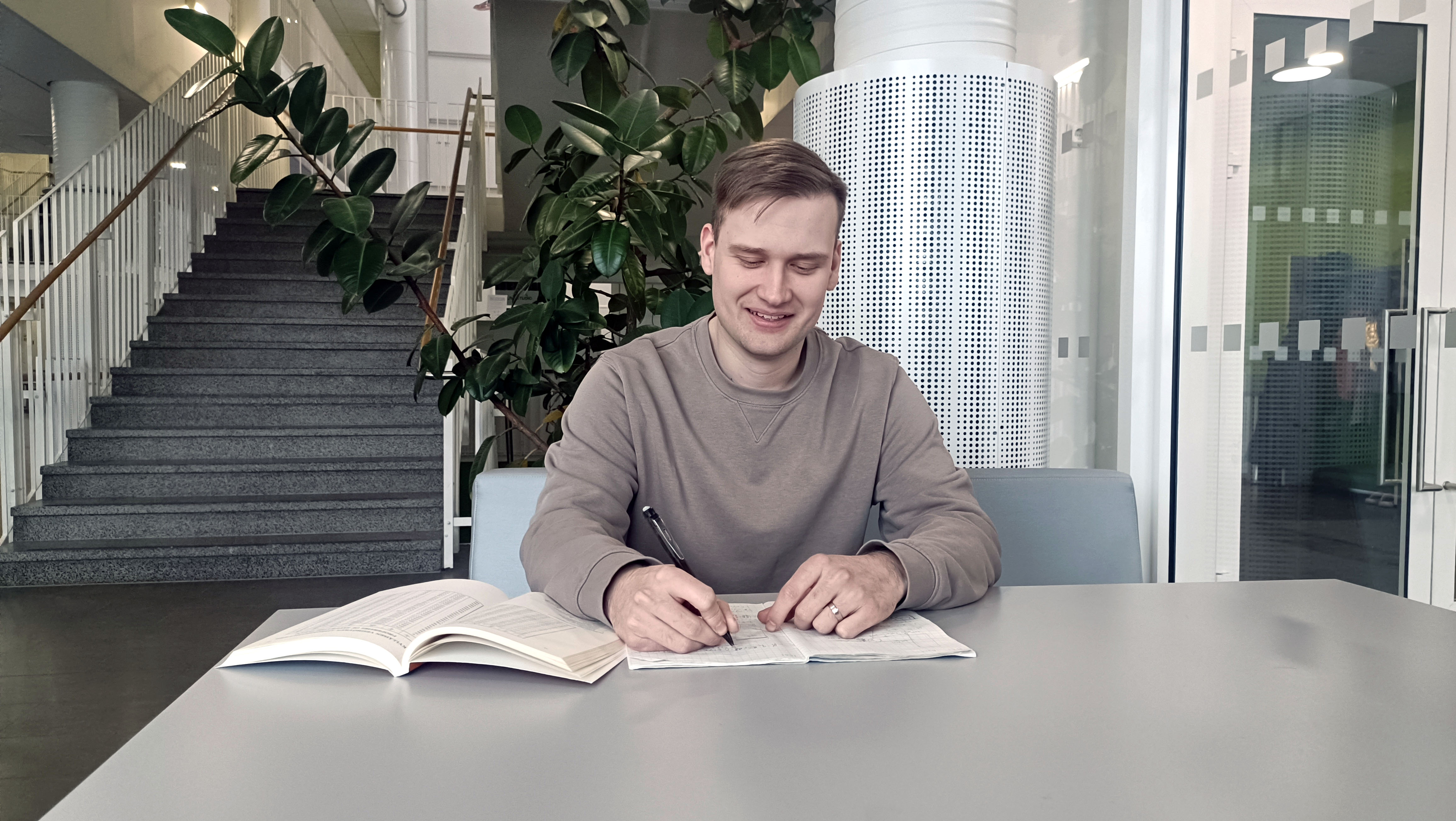 Matias Maja istuu pöydän ääressä ja tekee muistiinpanoja paperille.