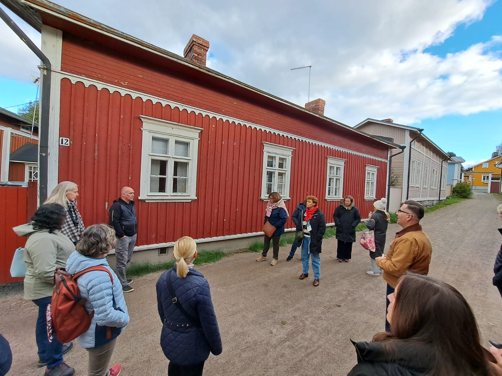 A group in Rauma's old town next to a red wooden house.