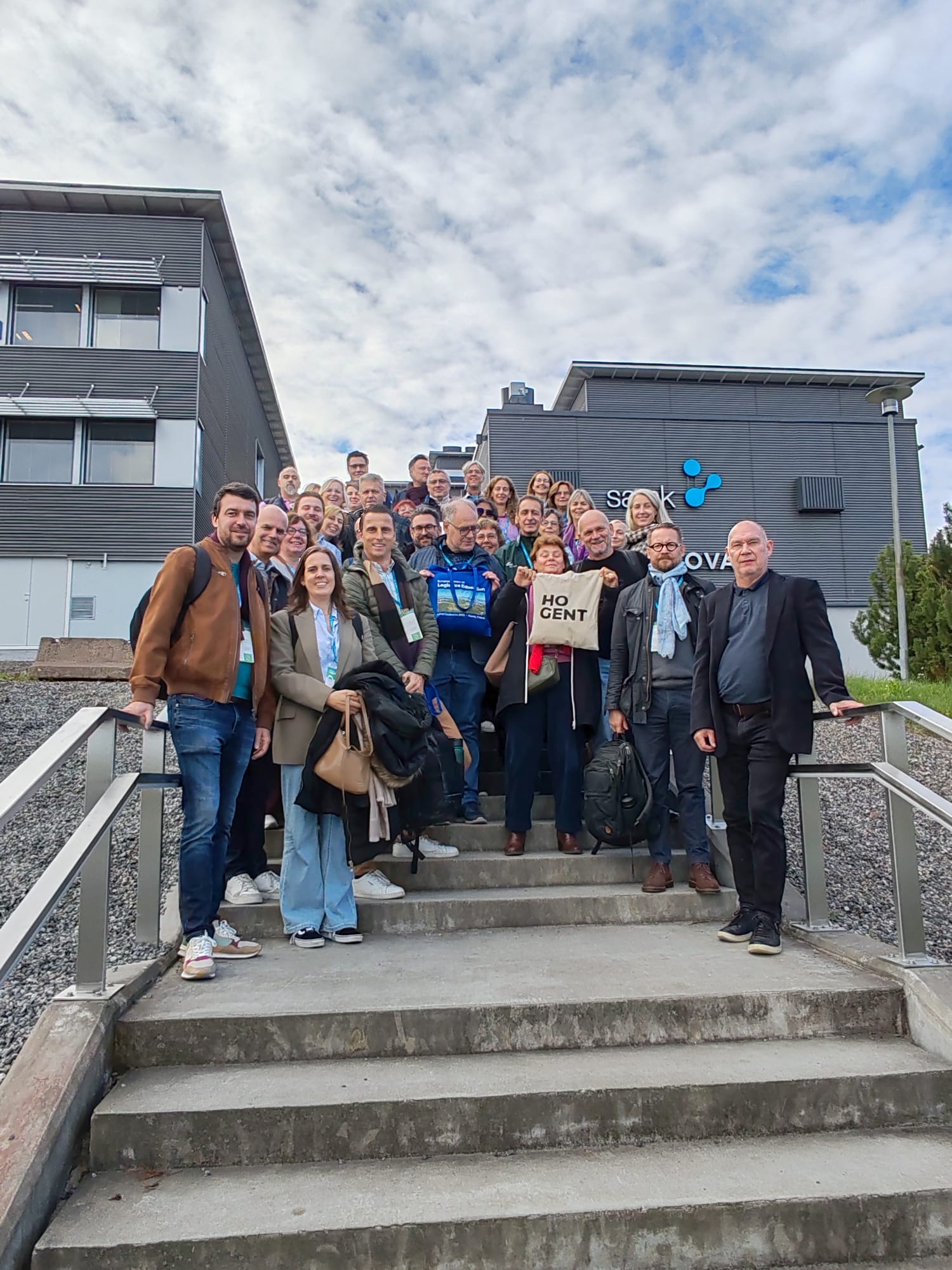 Group photo of conference participants, with the SAMK campus on Satamakatu in the background.