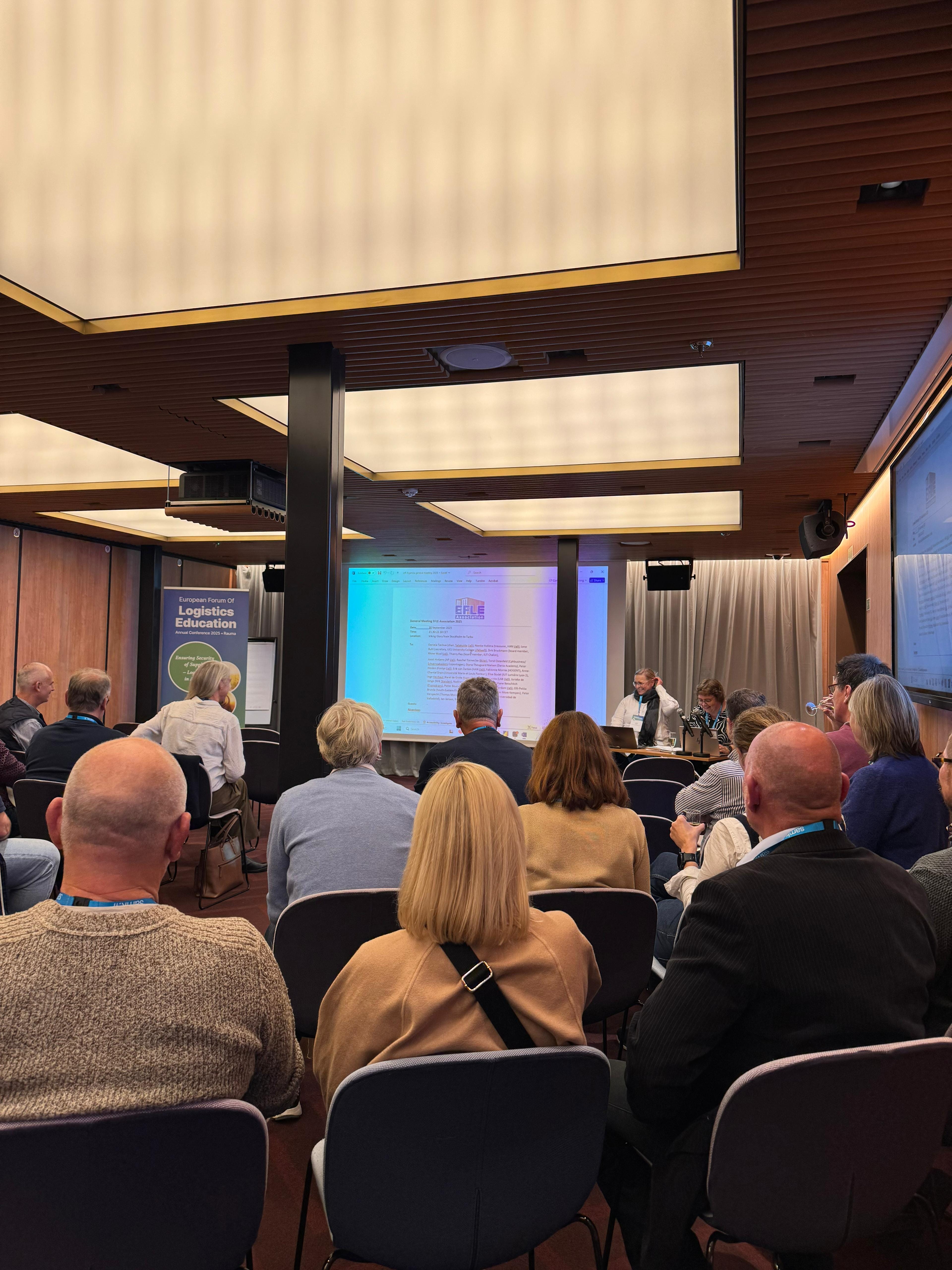 The audience is seated in the conference room.