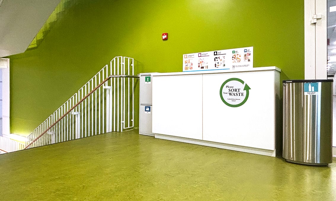 A waste sorting point with different bins for plastic, mixed waste, bottles, and cardboard.