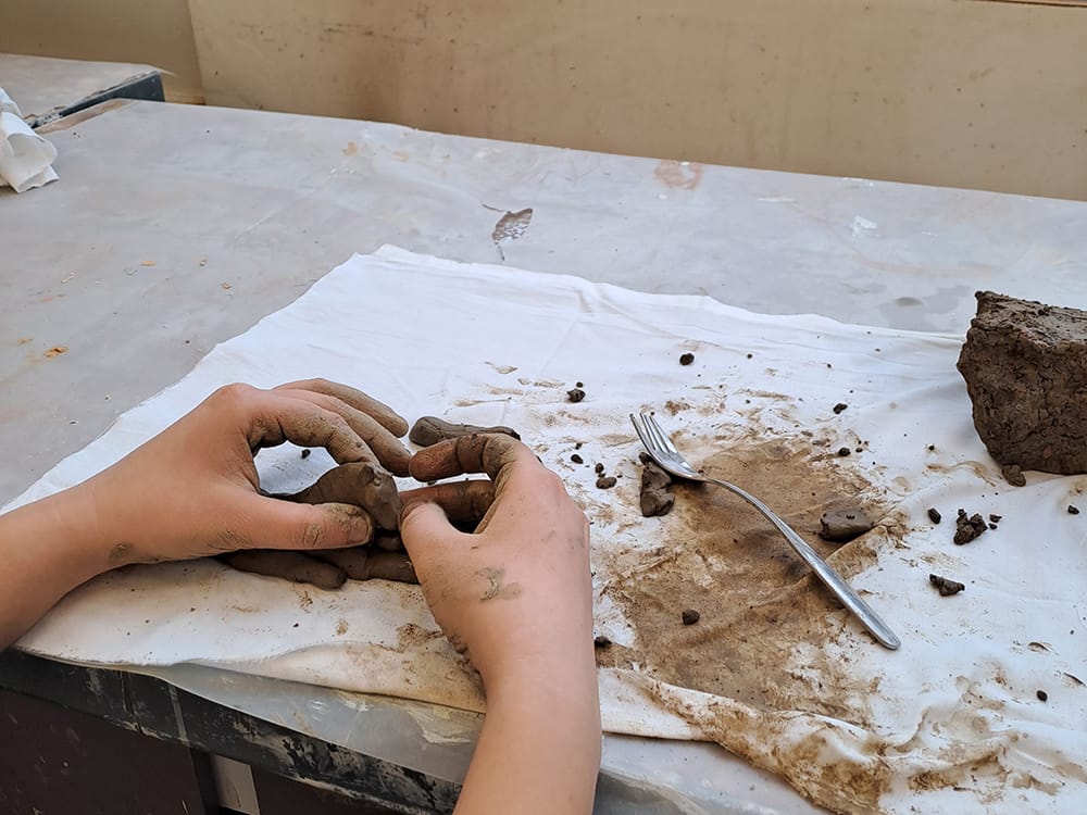 Osallistujat poistivat epäpuhtauksia juuri maasta nostetusta savesta.