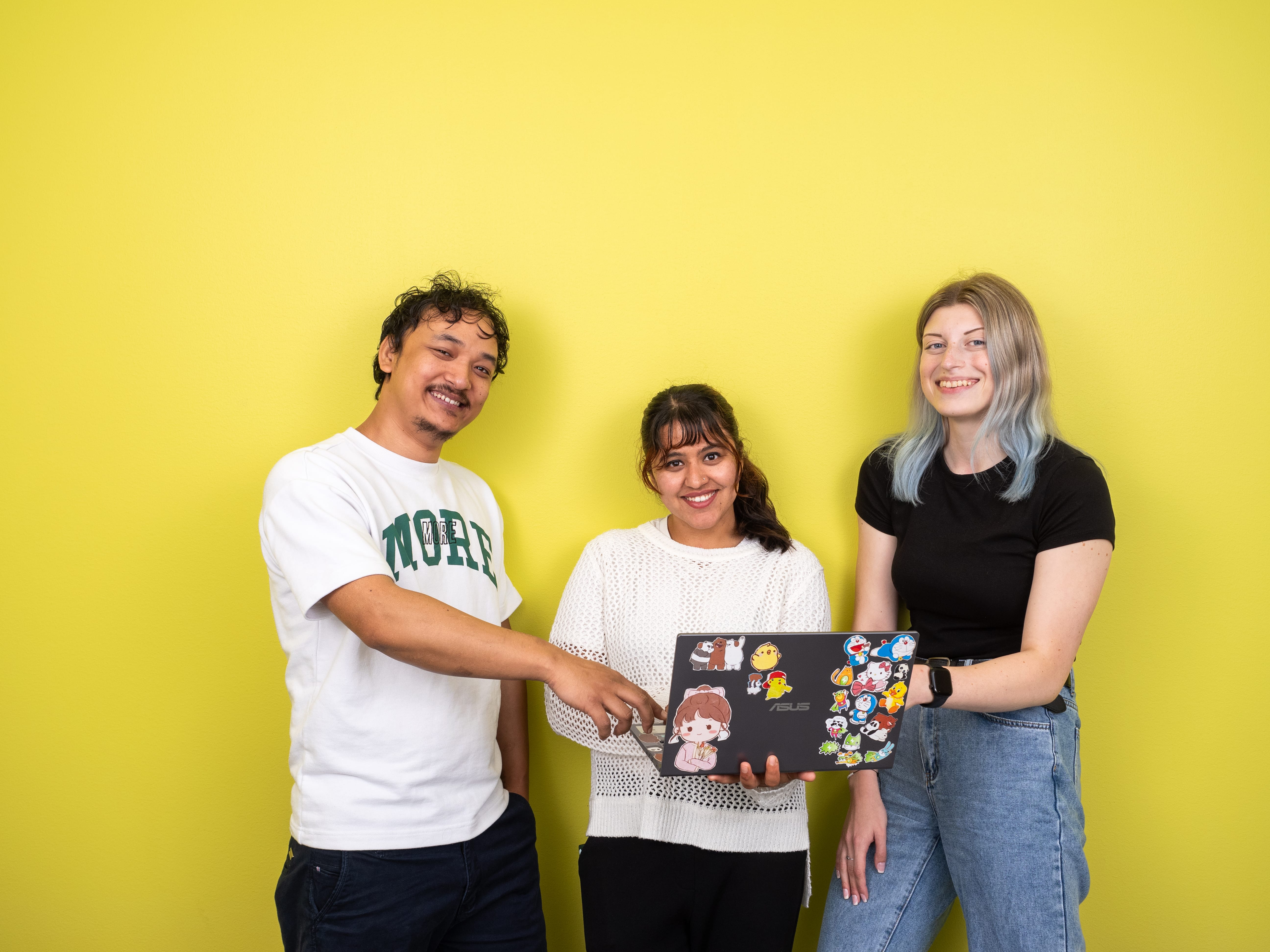 Opiskelijat hymyilevät kuvassa tietokoneen kanssa.