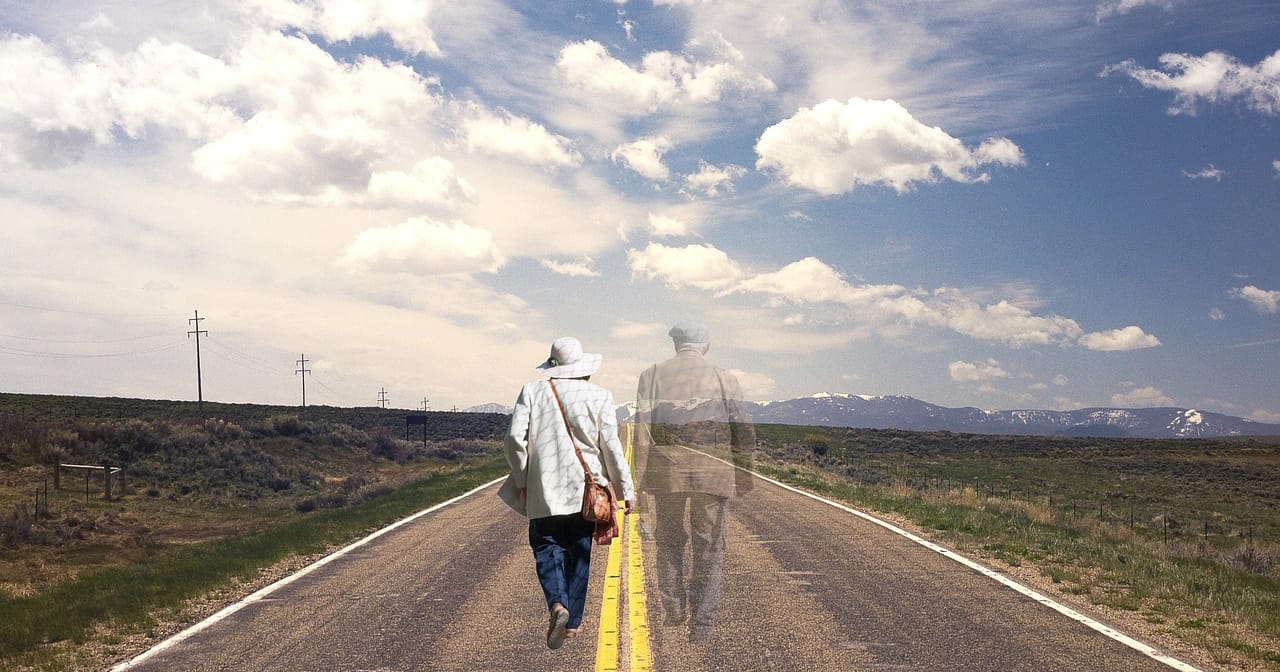 Nainen kävelee pitkin tietä, vieressä näkyy ääriviivat miehestä.