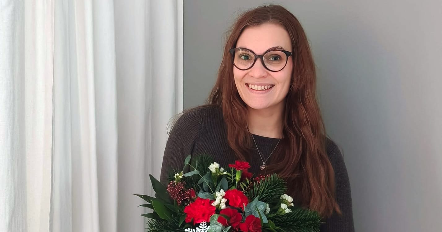 Jenni Kärkkäinen seisoo kukkapuska sylissään.