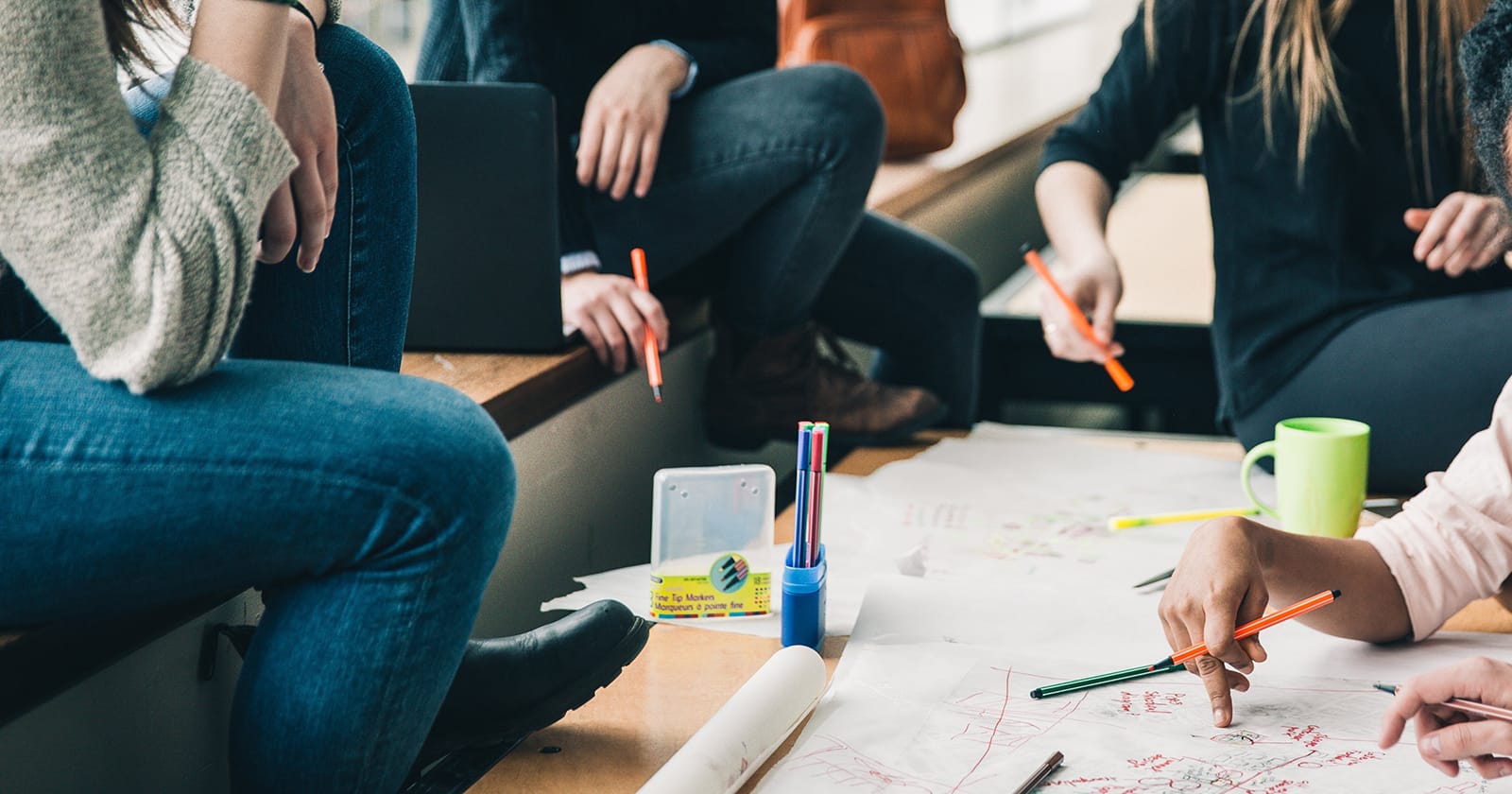 Lähikuva tiimityöpaperista, jonka ympärillä on opiskelijoita.