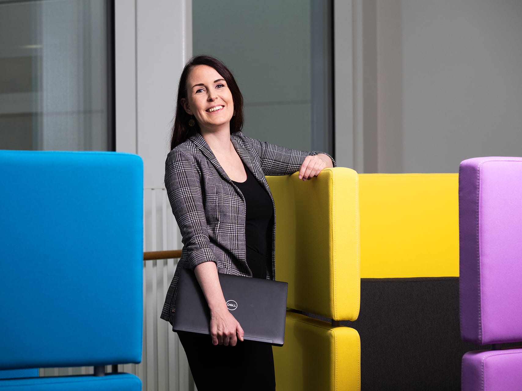 Opiskelija nojaa keltaiseen nojatuoliin ja hymyilee kameralle.