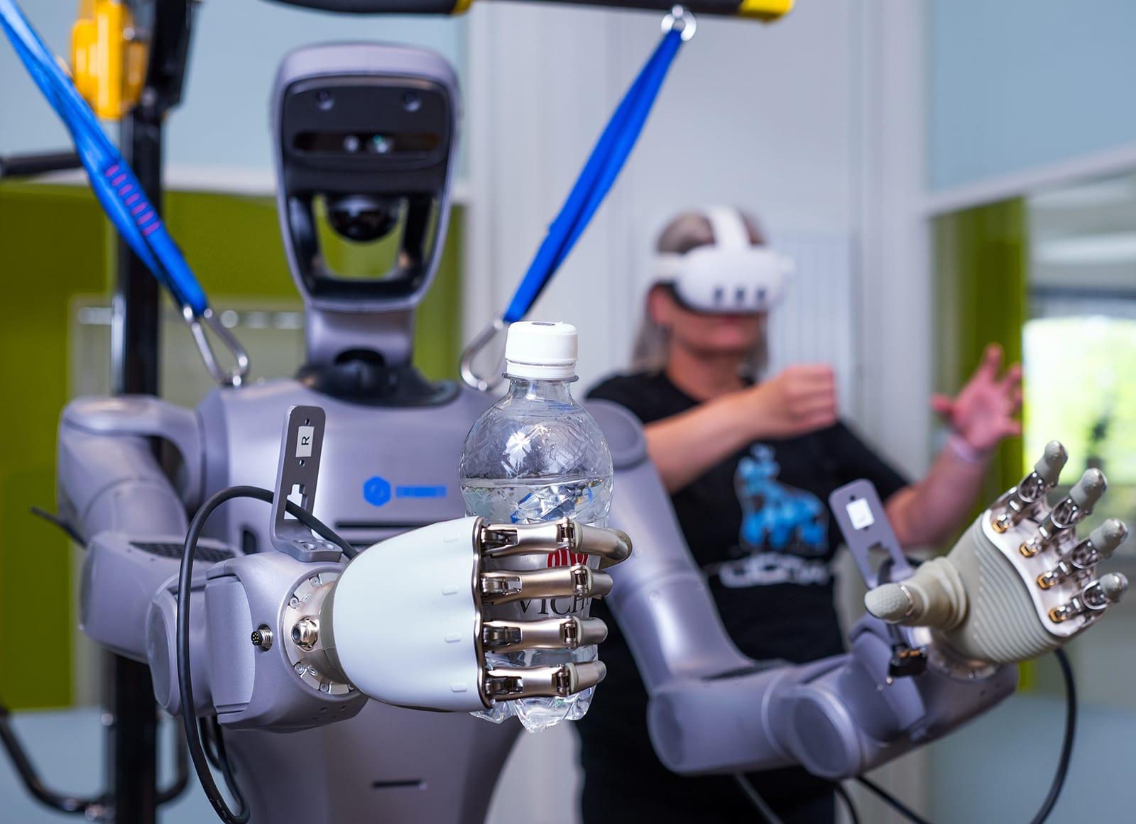 Humanoidirobotti pitelee vesipulloa VR-käyttäjän vieressä.